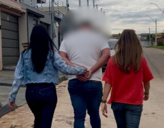 Imagem desfocada homem de costas preso por duas policiais civis