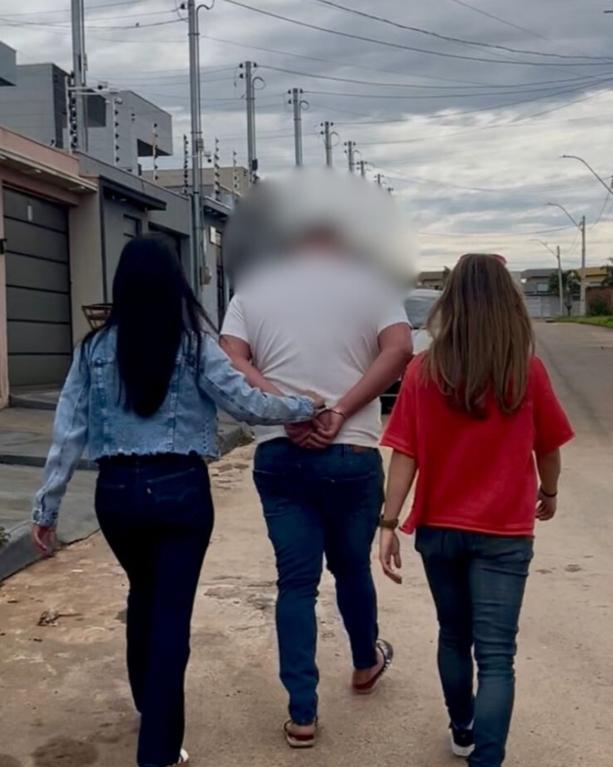 Imagem desfocada homem de costas preso por duas policiais civis