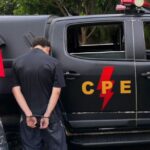 Imagem viatura da policia militar e três homens algemados