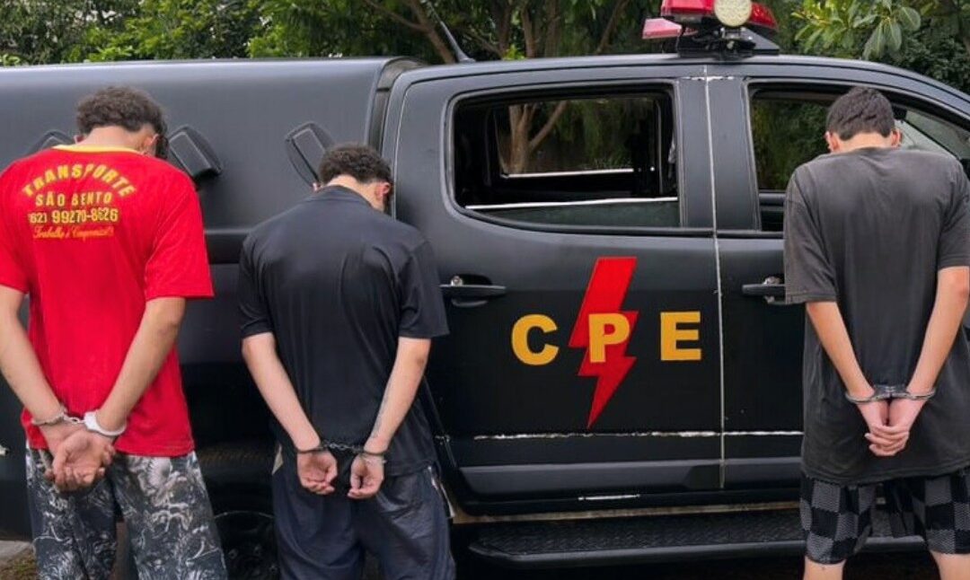 Imagem viatura da policia militar e três homens algemados