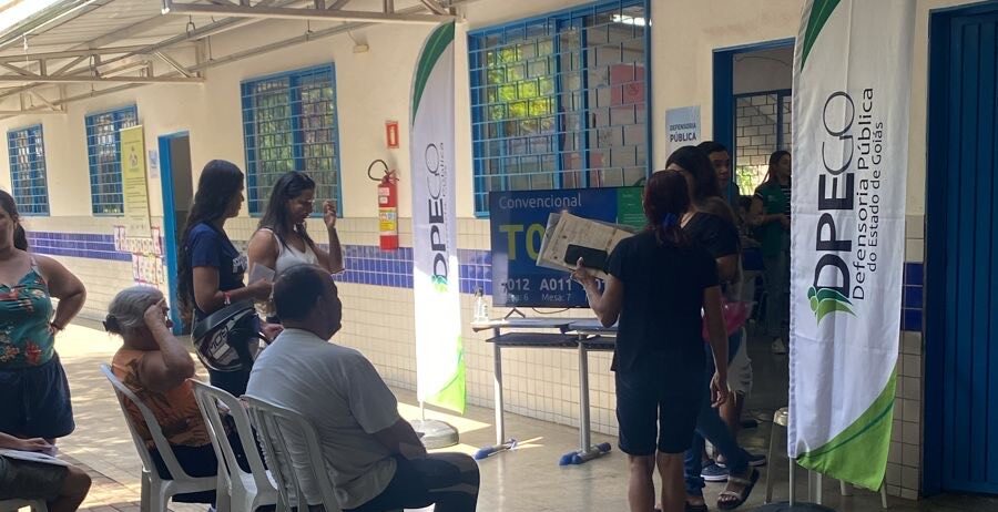 Imagem pessoas em pé e outras sentadas aguardando atendimento