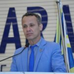 Imagem homem de terno azul falando ao microfone