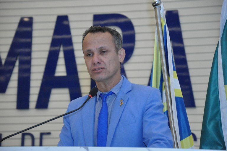 Imagem homem de terno azul falando ao microfone