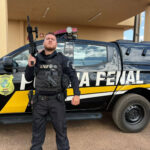 Imagem homem fardado com roupa preta segurando uma arma