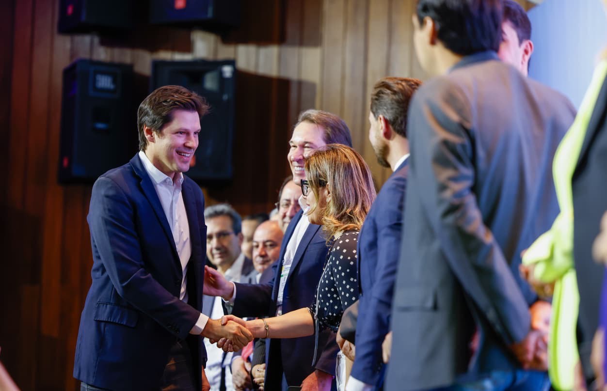 Imagem homem de terno cumprimentado pessoas no palco