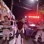 Imagem homem de costas preso ao lado policiais militares