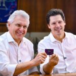 Imagem dois homens sorrindo de camisa branca segurando cartão