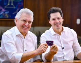 Imagem dois homens sorrindo de camisa branca segurando cartão