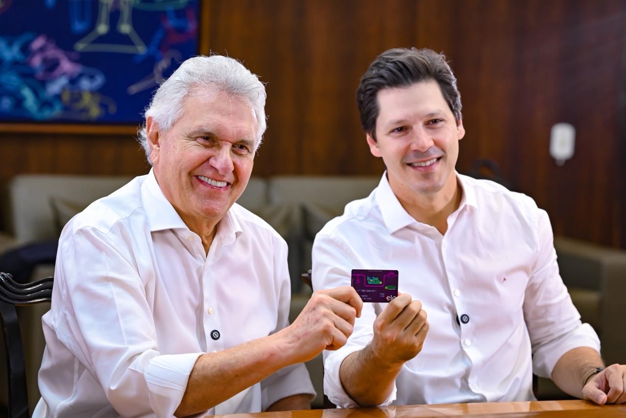 Imagem dois homens sorrindo de camisa branca segurando cartão