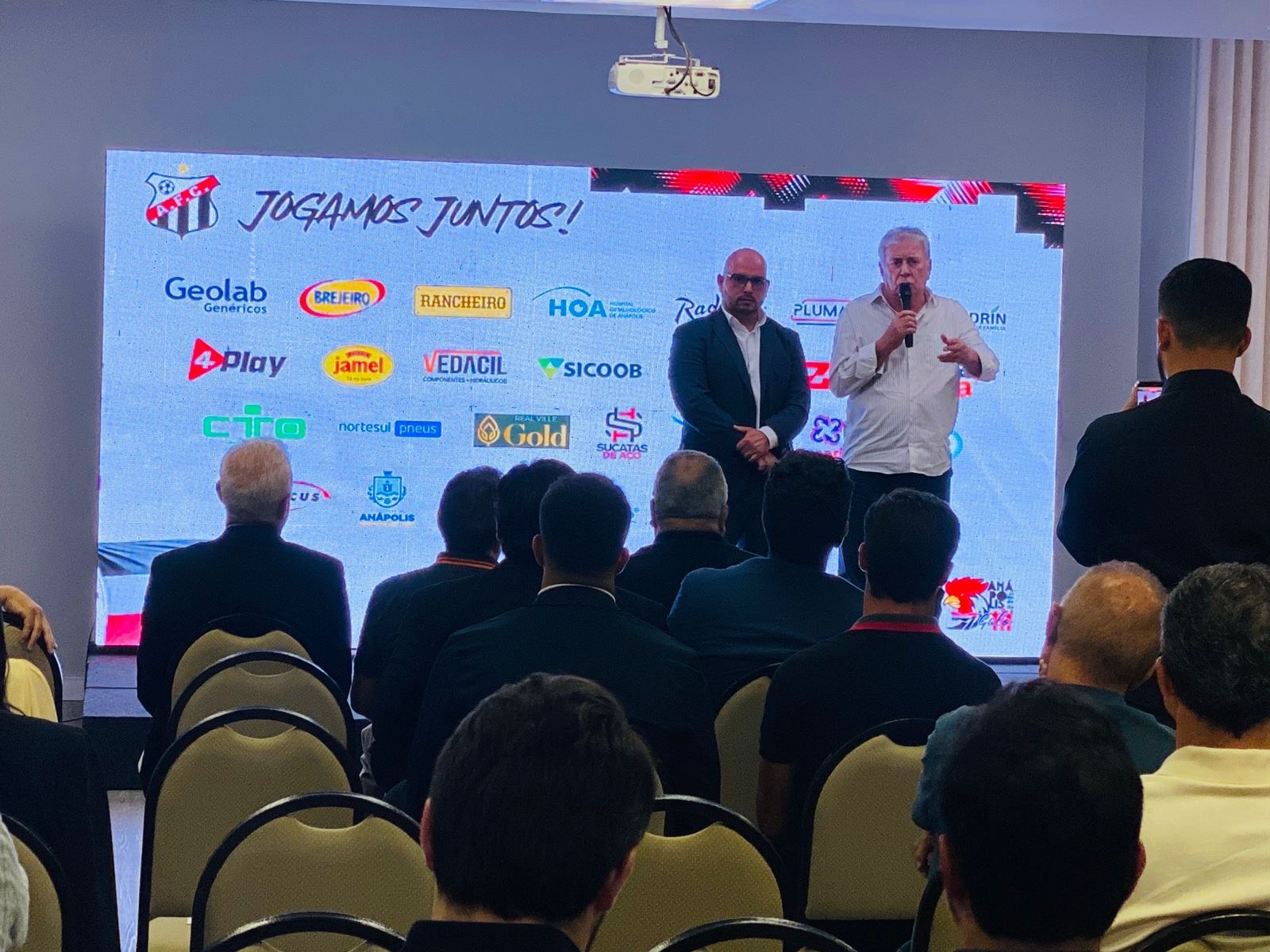 Imagem dois homens falando para plateia