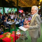 Imagem homem sorridente de terno falando para plateia