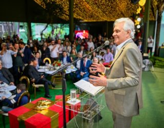 Imagem homem sorridente de terno falando para plateia