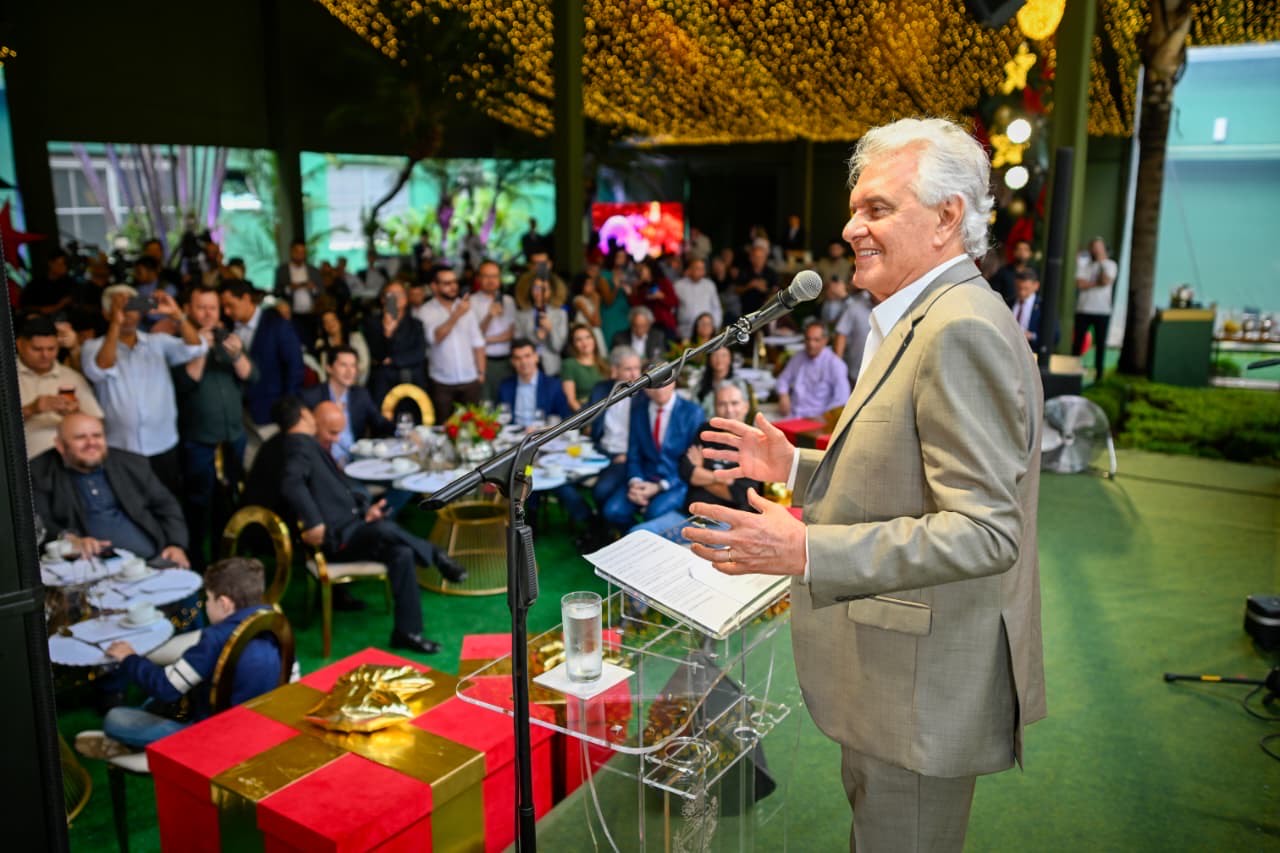 Imagem homem sorridente de terno falando para plateia