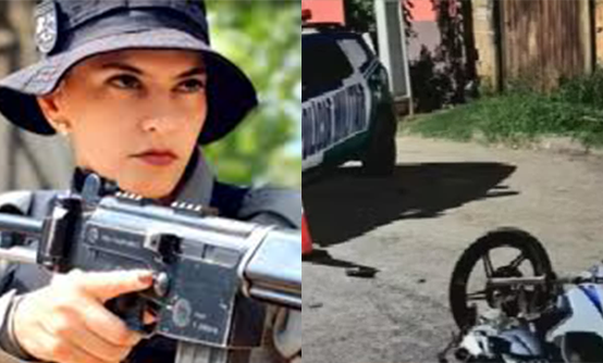 Imagem polcial segurando arma longa ao lado moto caída e viatura