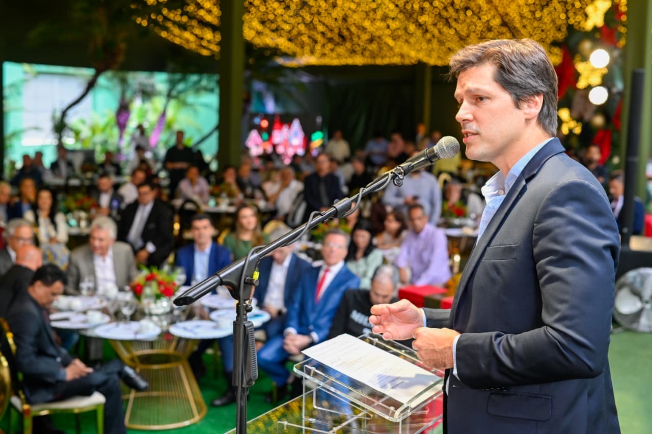 Imagem homem de terno falando ao microfone para plateia