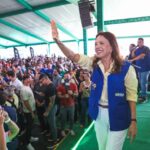 Imagem mulher sorridente com o braço direito erguido