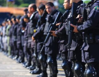 Imagem policiais militares de farda preta segurando arma longo