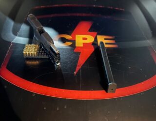 Imagem arma de fogo em cima de capô da viatura da CPE