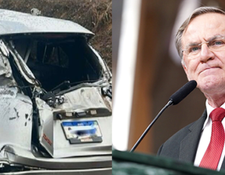 Imagem carro destruído ao lado homem de terno gravata vermelha