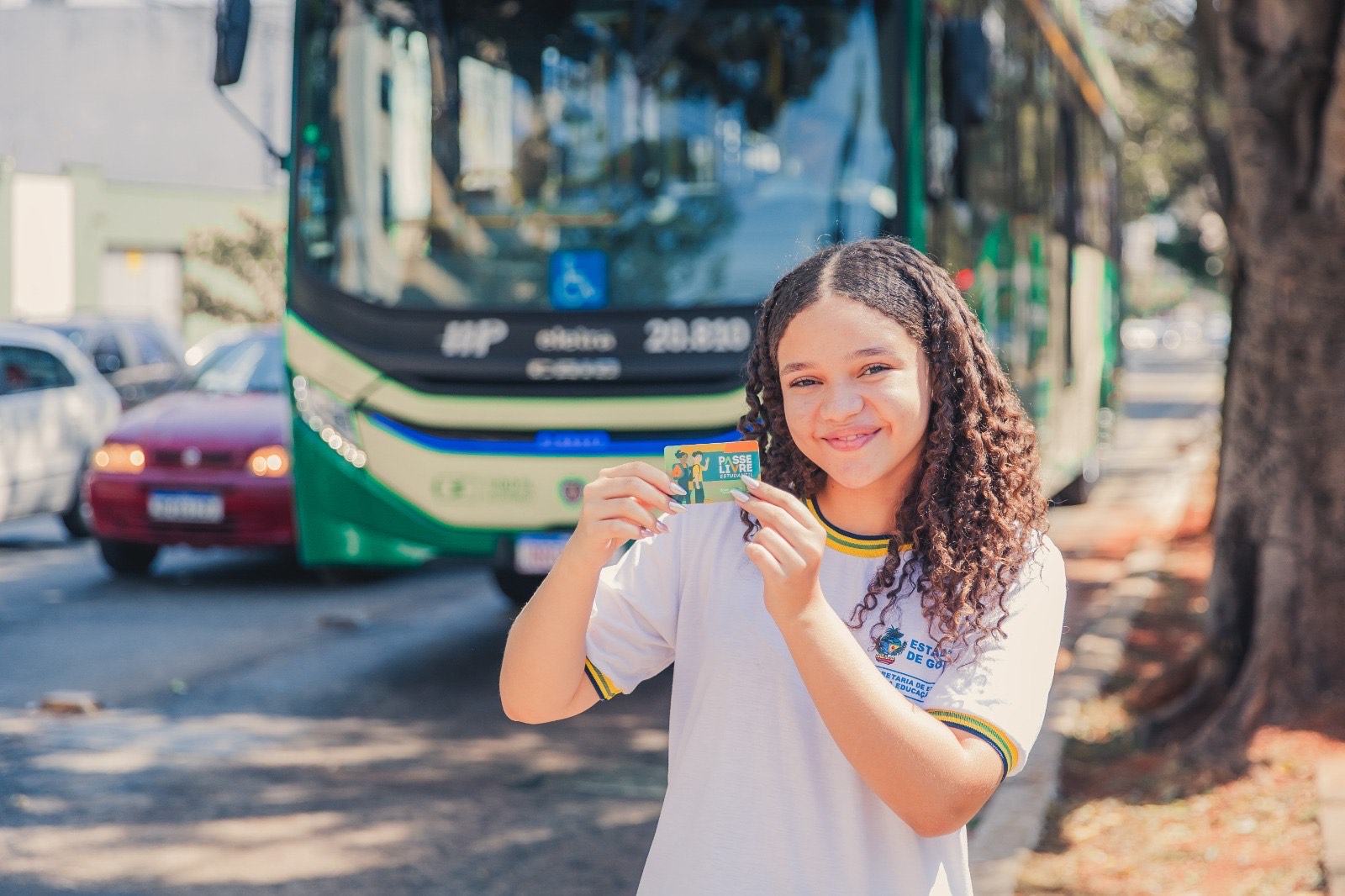 Imagem jovem sorrindo segurando o cartão do Passe Livre Estudantil