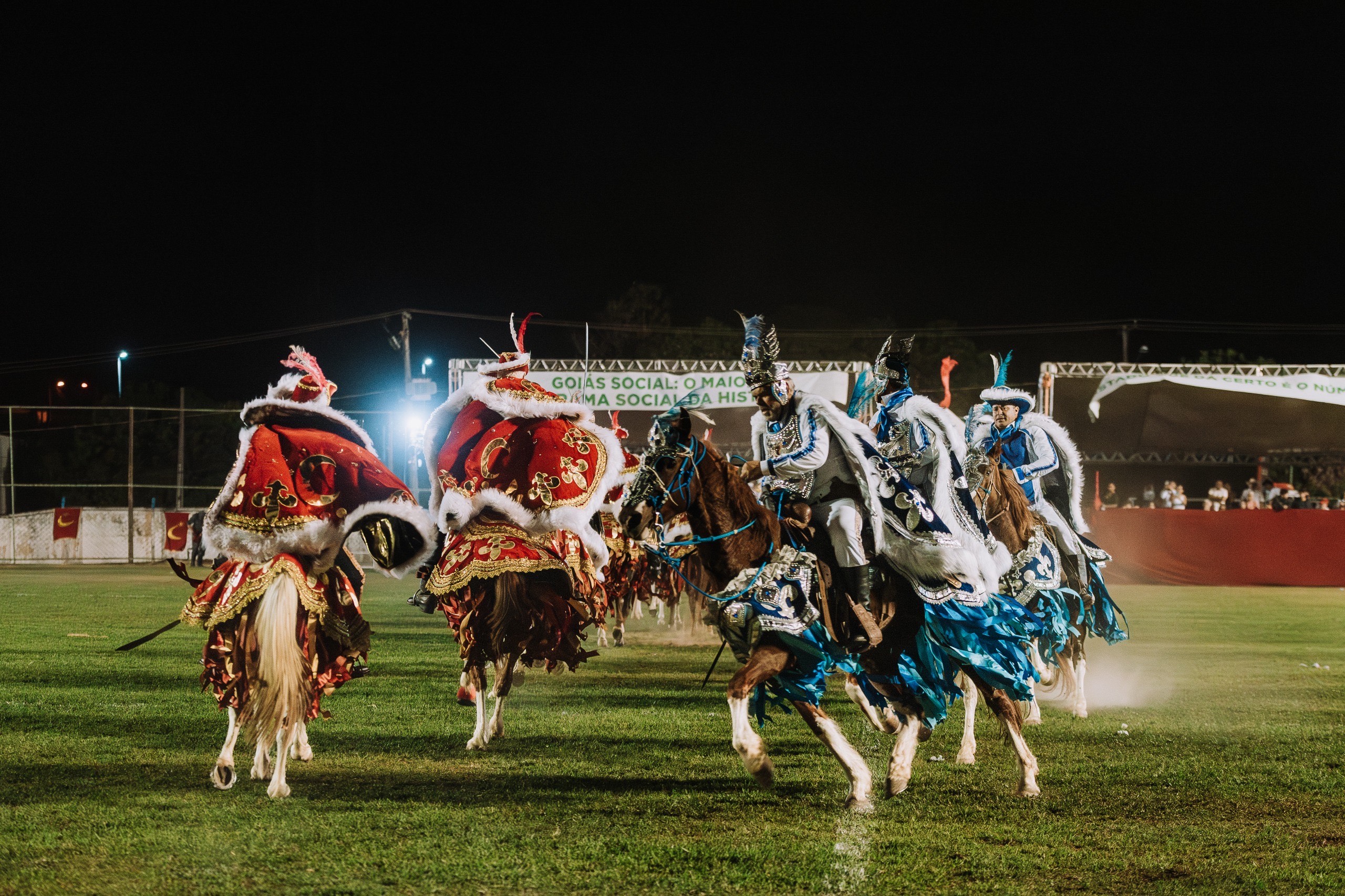 Imagem homens em cima de cavalos com vestimentas vermelha e azul