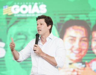 Imagem homem de camisa branca falando ao microfone