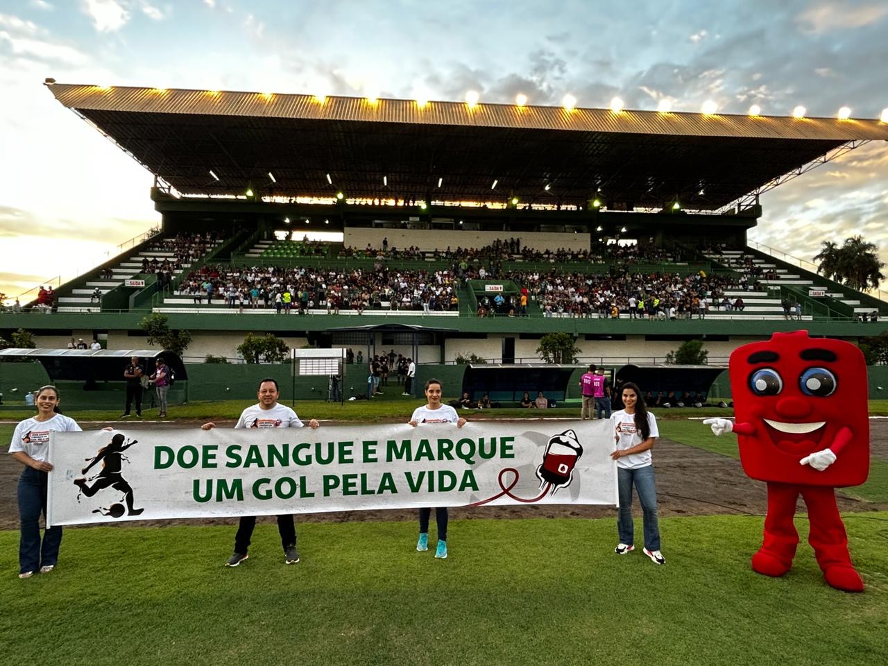 Imagem pessoas dentro de campo segurando faixa