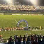 Imagem jogadores no centro do gramado em fila