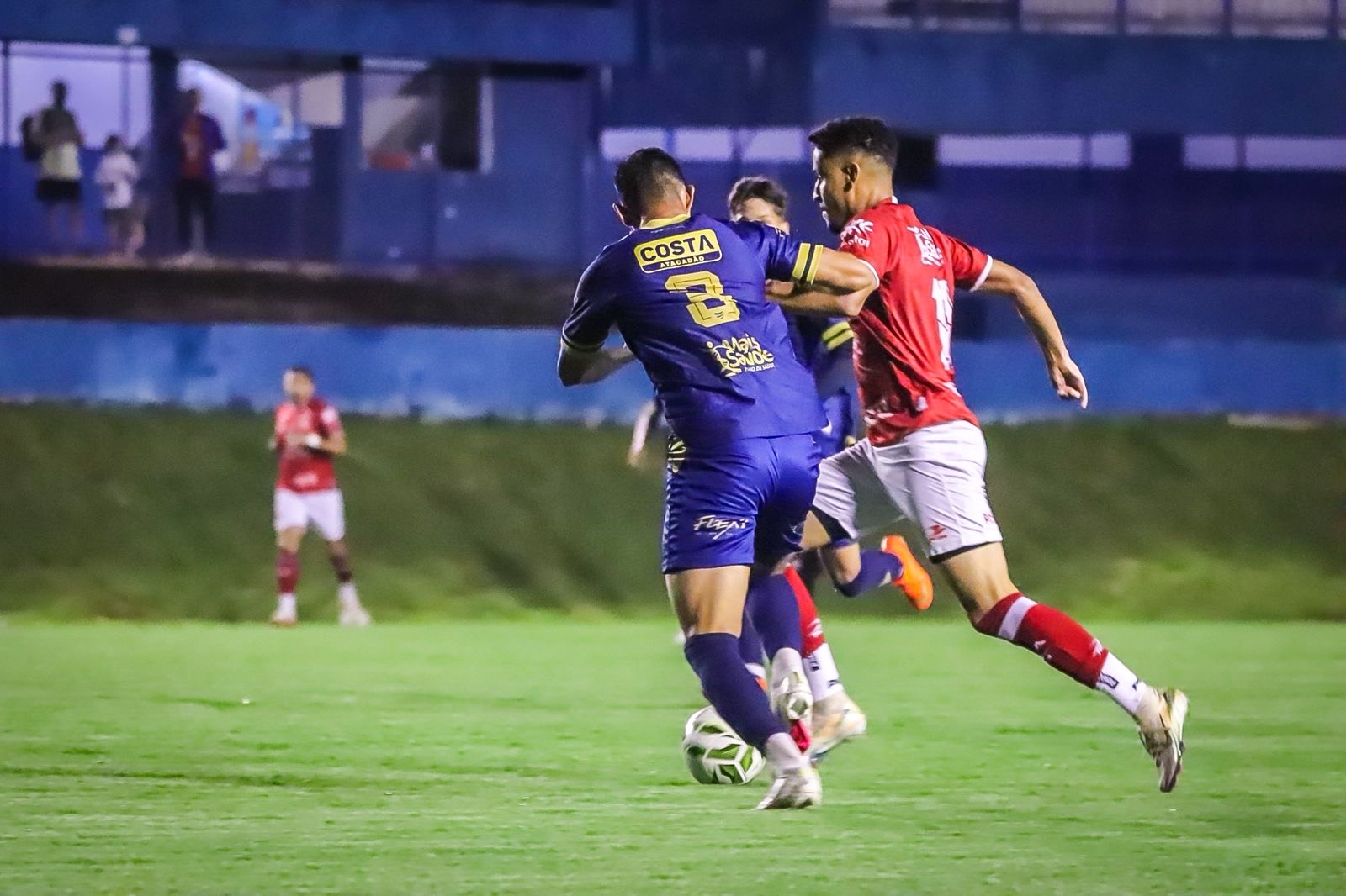 Imagem jogadores de azul e vermelho disputando a bola