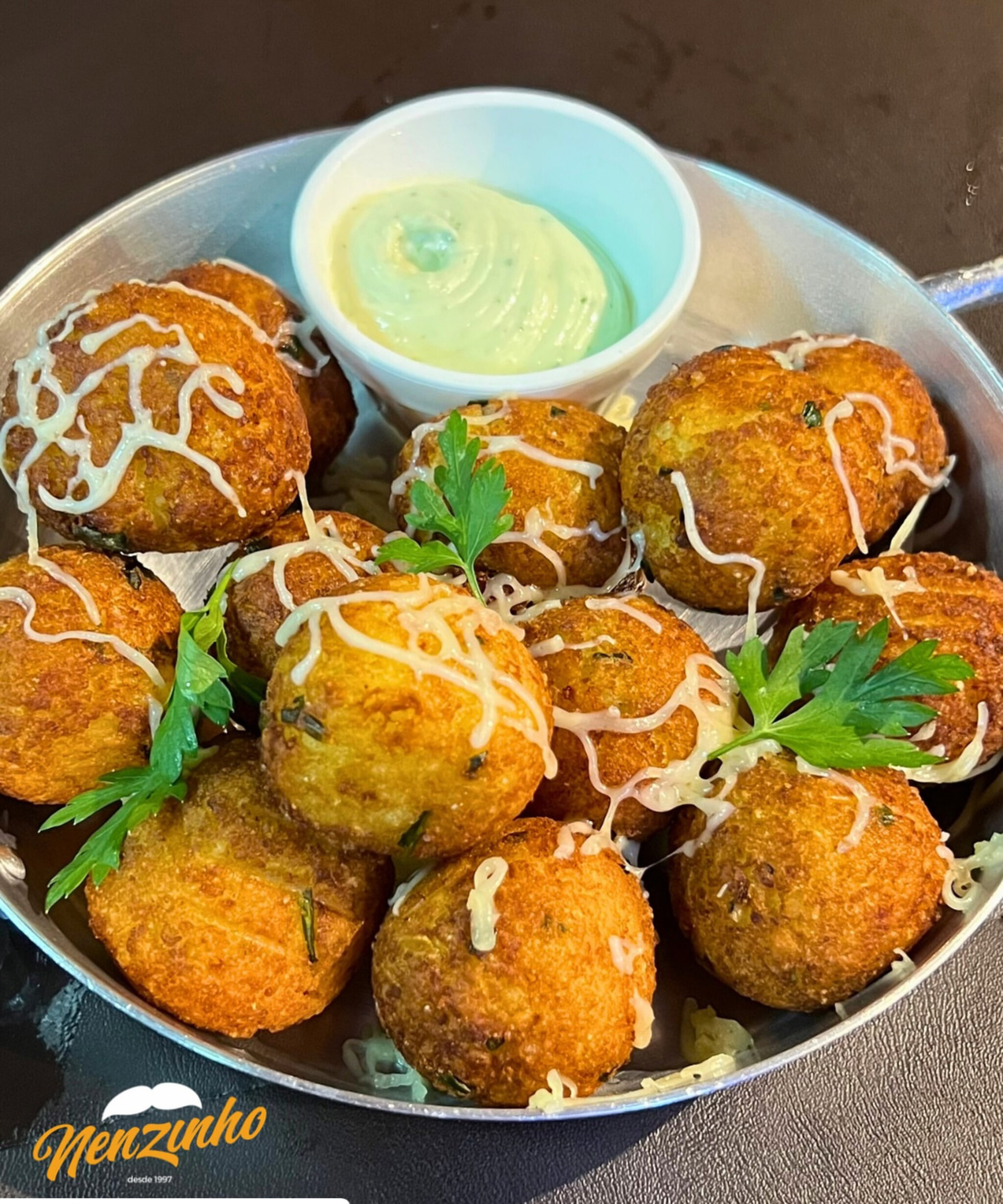 Imagem bolinhos em uma travessa com molho branco ao lado