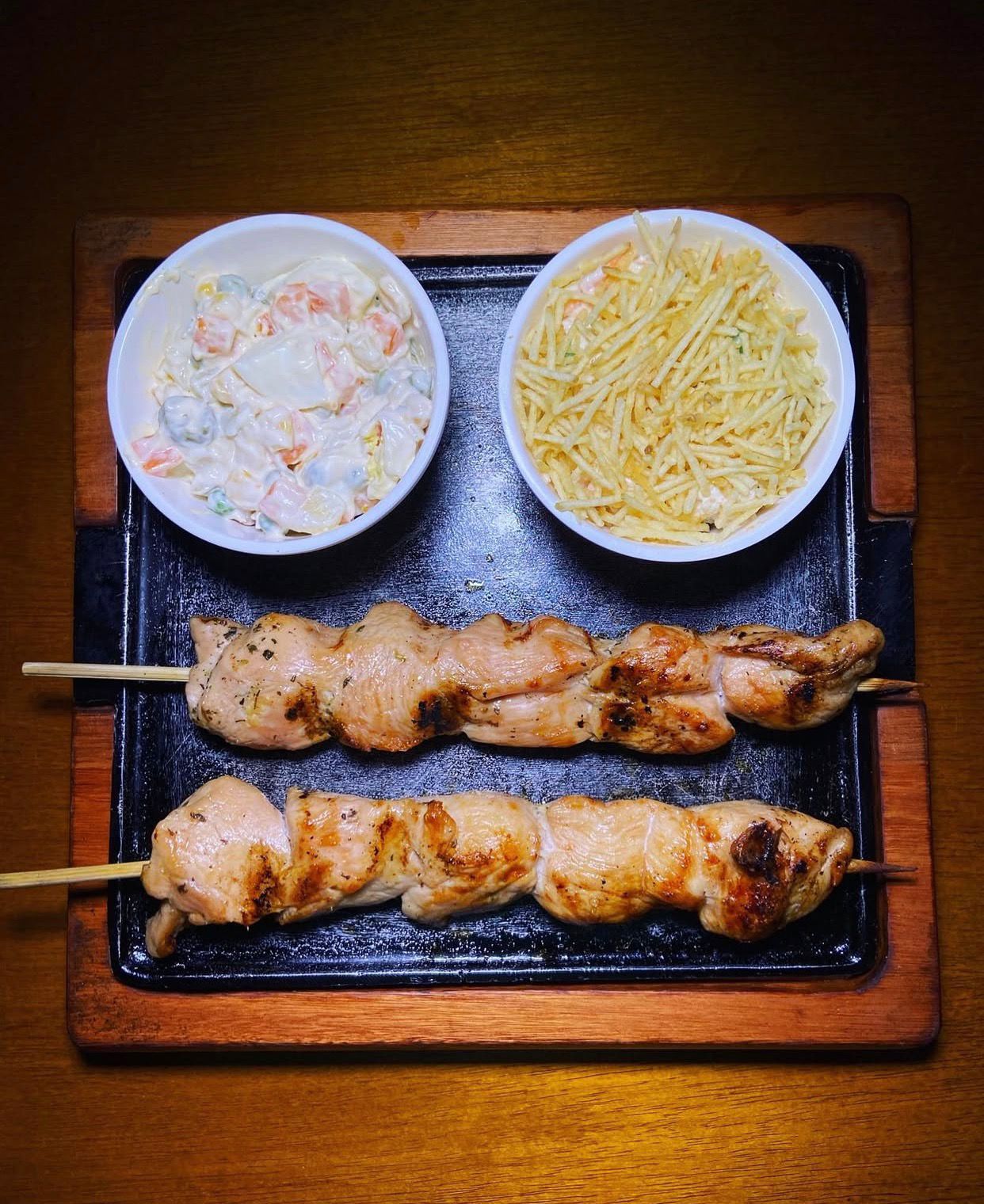 Imagem dois churrasquinhos no espeto e dois acompanhamentos