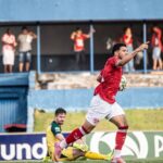 Imagem goleiro sentado e atacante em pé comemorando