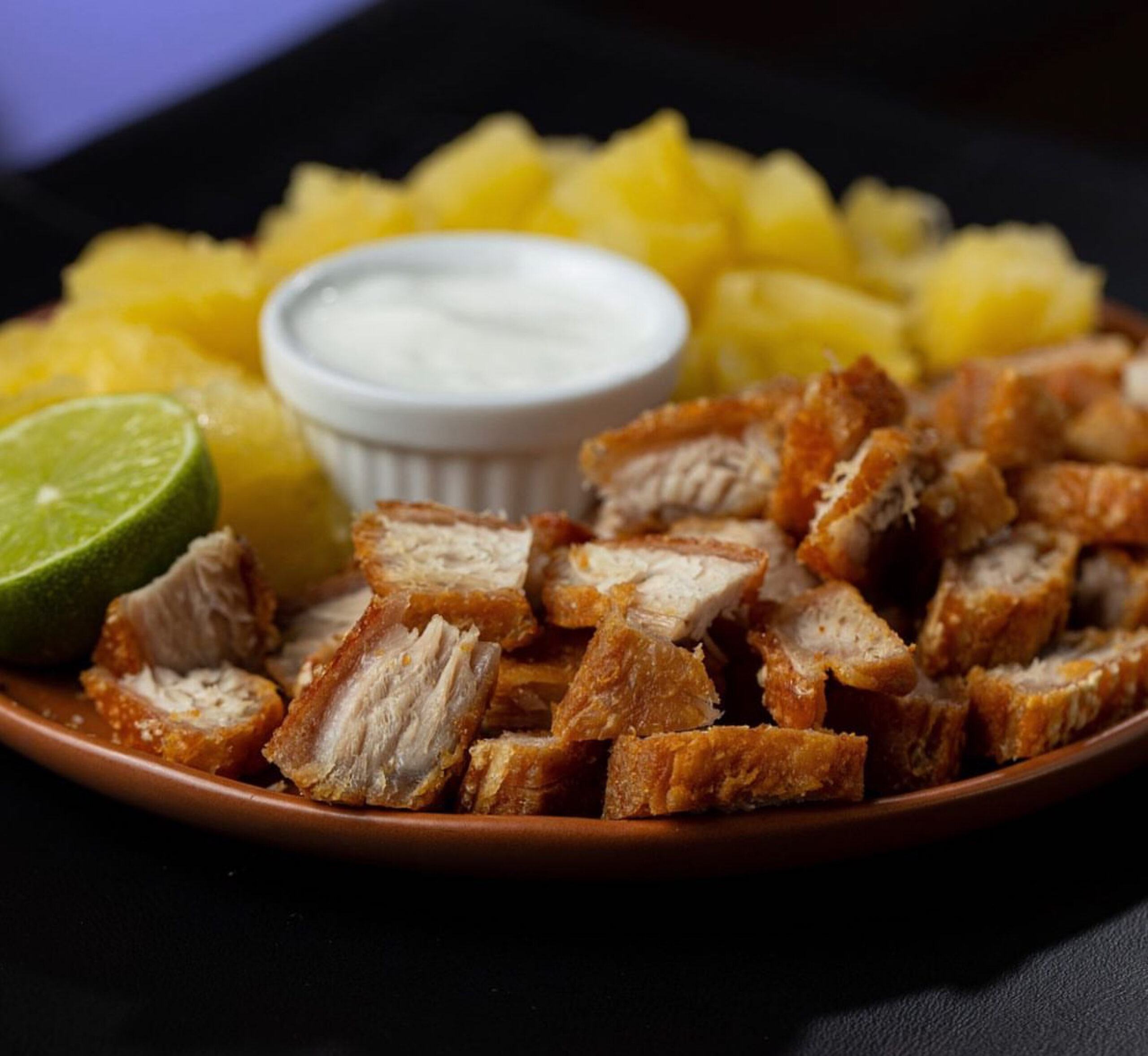 Imagem porção de carne com mandioca ao centro copo com molho branco