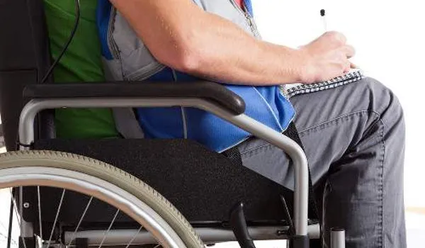 Imagem pessoa na cadeira de rodas escrevendo no caderno