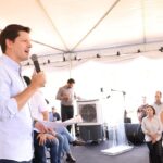 Imagem homem de camisa branca falando ao microfone