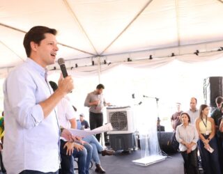 Imagem homem de camisa branca falando ao microfone