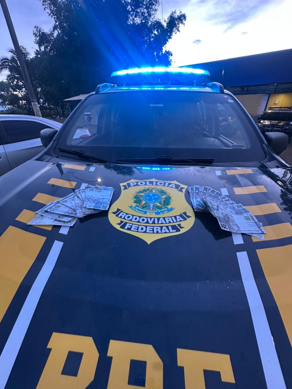 Imagem capô de carro da policia com notas em cima