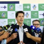 Imagem homem terno preto falando vários microfones