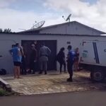 Imagem policiais e pessoas em frente uma casa