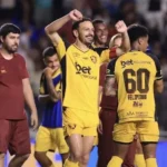 Imagem jogadores com camisa amarela comemorando ao fundo jogadores com camisa grena