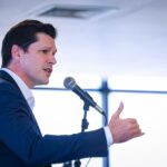 Imagem homem de terno falando ao microfone