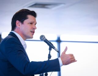 Imagem homem de terno falando ao microfone