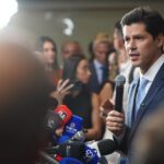 Imagem homem segurando microfone em entrevista coletiva