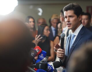 Imagem homem segurando microfone em entrevista coletiva