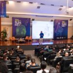 Imagem homem em palco e publico em teatro lotado