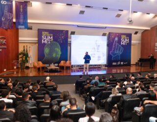 Imagem homem em palco e publico em teatro lotado