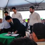 Imagem homem assinando documento no palco