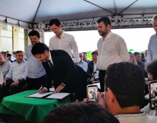 Imagem homem assinando documento no palco