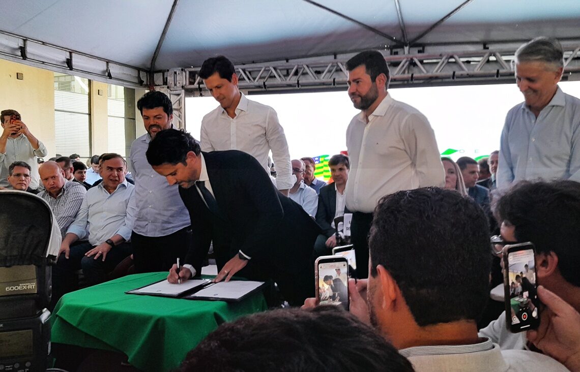 Imagem homem assinando documento no palco