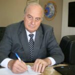 Imagem homem de terno e gravata com caneta na mão assinando documento